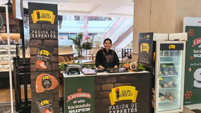 Isla de exhibición con banners y vitrina refrigerada montada en pasillo de centro comercial